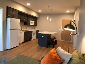 a kitchen and a living room with a refrigerator and a sink